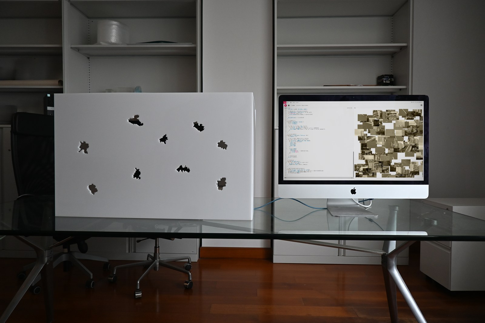 A perforated white panel beside a screen displaying fragmented city images.